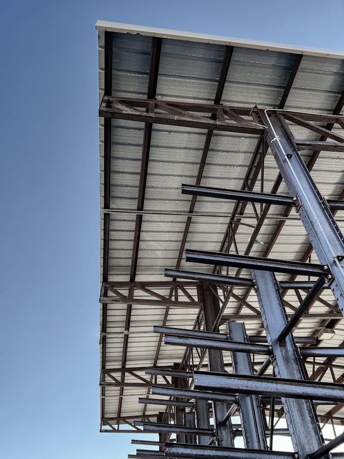 An industrial steel structure under construction against a clear blue sky, showcasing architectural design.